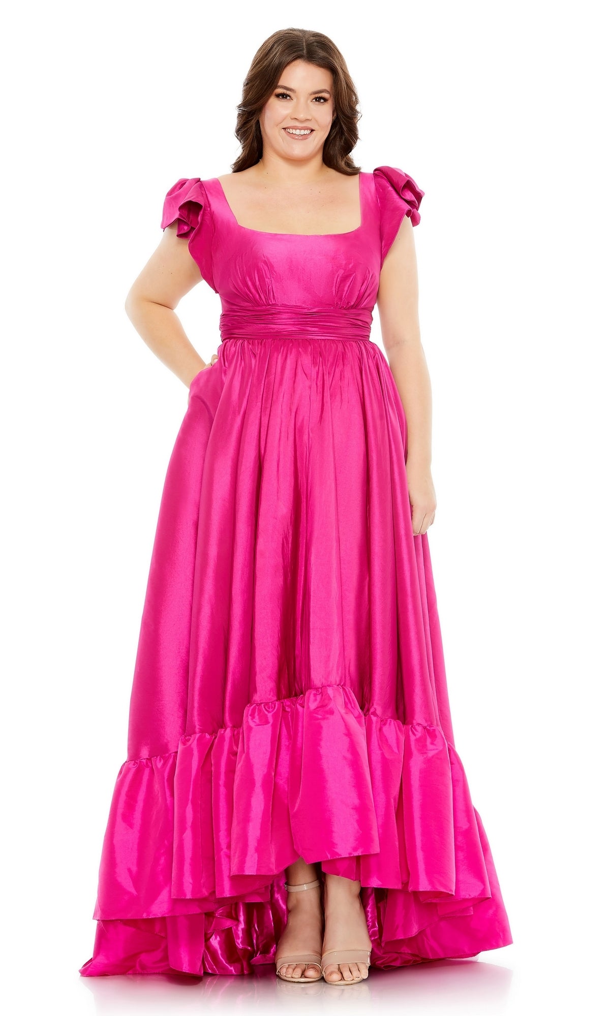 A woman stands smiling with her hands by her sides, wearing the Long Plus-Size Formal Dress 68150 by Mac Duggal in magenta pink, featuring flutter sleeves and a ruffled hem.